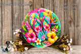 A vibrant and colorful wreath of tropical flowers, including hibiscus blooms, is displayed on a wooden surface.