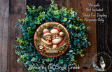 A wreath made of green leaves and a circular ornament featuring Santa Claus and a message, with a wooden background.
