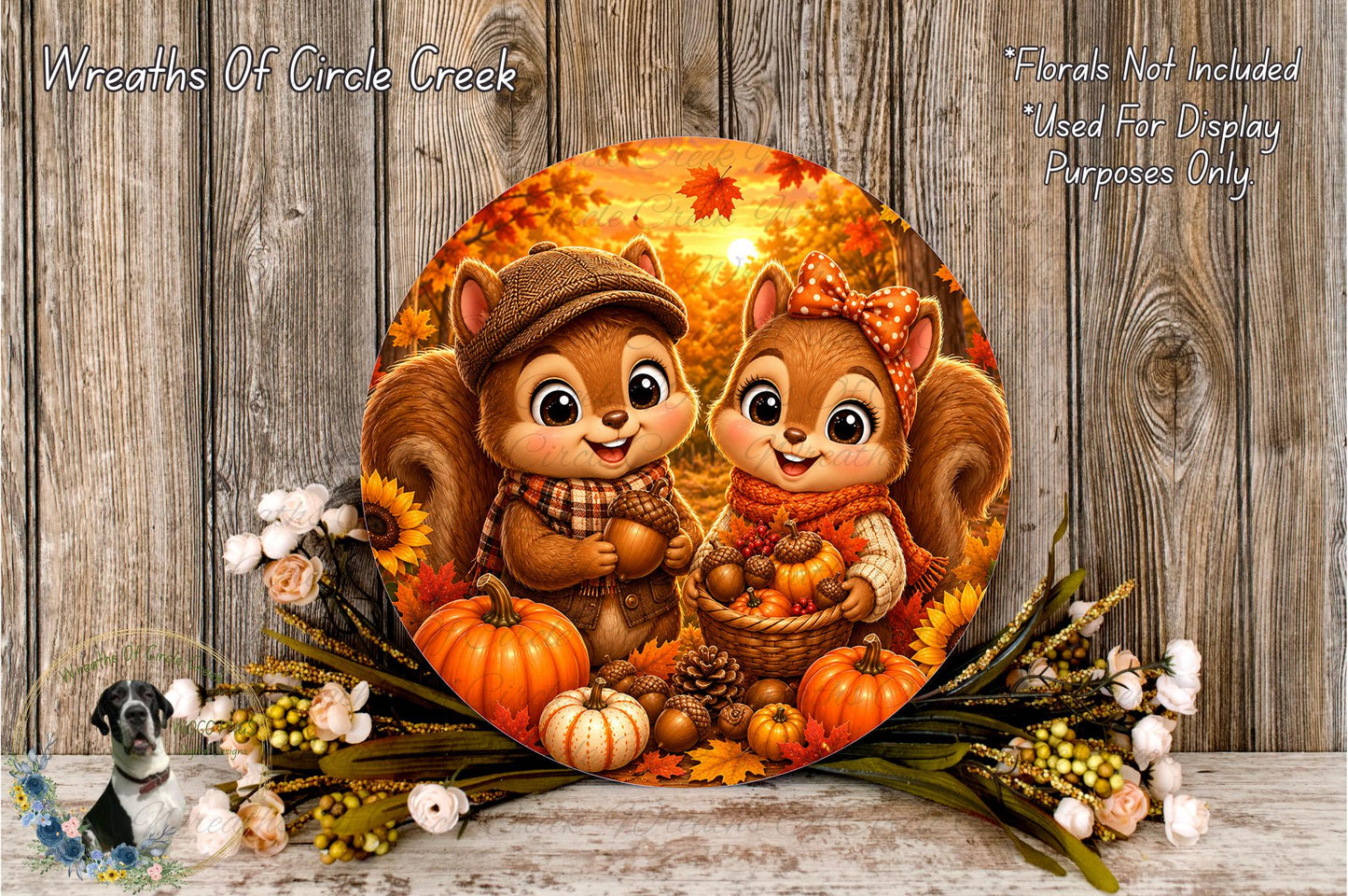 A round, decorative wreath featuring two cartoon squirrels, one wearing a hat and the other a bow, surrounded by autumn-themed elements such as pumpkins, leaves, and flowers.