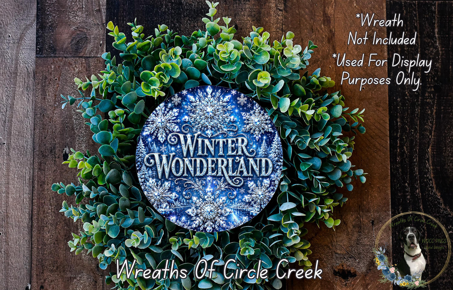 A wreath made of green leaves and blue snowflakes, with the text "Winter Wonderland" displayed on it. The wreath is placed on a wooden surface, and there is a small dog in the bottom right corner of the image.