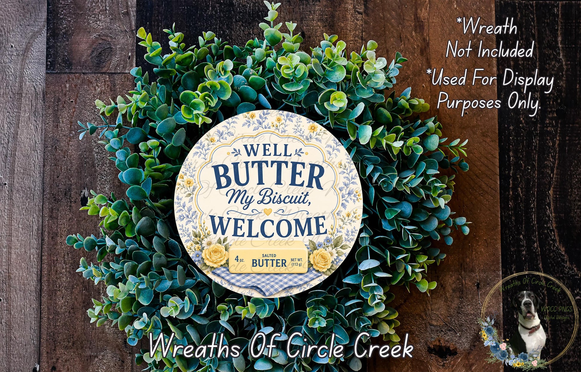 a wreath made of green leaves and a circular sign with text, placed on a wooden surface.