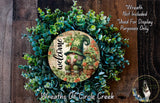 a wreath with a gnome and greenery, and a sign that reads "Welcome" in the center. The sign is surrounded by a lush, colorful wreath.