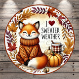 A cheerful illustration of a fox wearing a cozy sweater and surrounded by autumn elements, including a pumpkin, leaves, and a mug of hot beverage, with the text "I ❤️ sweater weather" displayed.