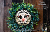 a wreath with a cow's face and the word "Welcome" written on it, surrounded by green foliage.