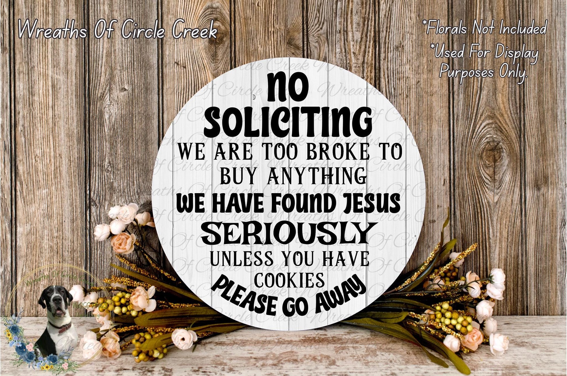 a sign with a humorous message, surrounded by flowers and a wooden background.