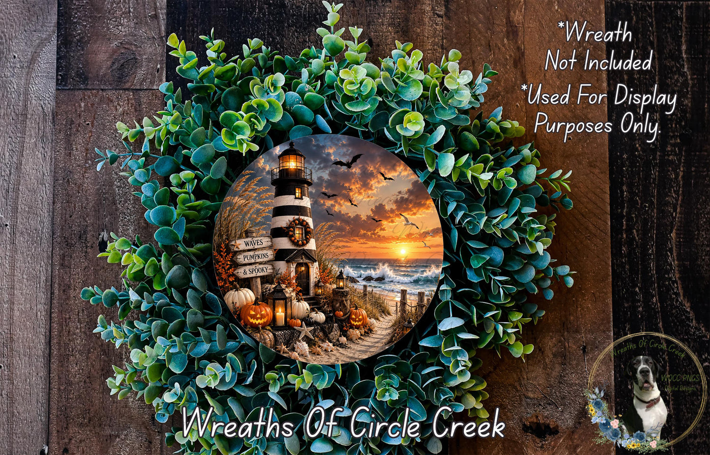 A wreath with a lighthouse and a sunset scene, surrounded by greenery, is displayed on a wooden surface.