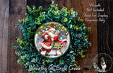 A wreath made of green leaves and a Santa Claus illustration, with the text "Merry & Bright" displayed on it.