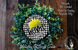The image is a wreath made of green foliage and a tennis ball, with a black and white sign that reads "If we're not home, check the court" in the center.