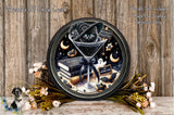 A decorative plate featuring a black cat wearing a witch's hat, surrounded by Halloween-themed elements such as a martini glass, books, flowers, and bats.