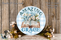 a round sign with the text "AMAZING GRACE" and an illustration of an open book with flowers on the cover, surrounded by a floral arrangement.