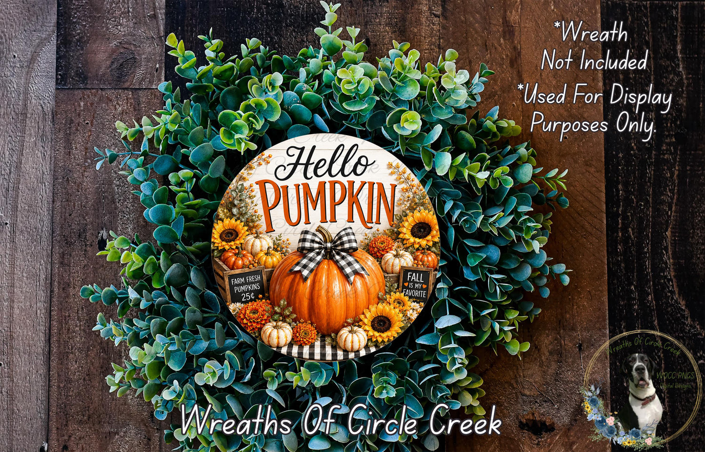 a wreath made of various fall-themed elements, including a pumpkin, sunflowers, and greenery. The wreath is displayed on a wooden surface, and there is a small dog in the background.