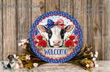 a decorative sign with a cow's face, surrounded by flowers and a bow, placed on a wooden surface.