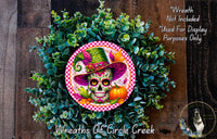 A wreath made of green leaves and a colorful skull wearing a hat, with a pumpkin and other decorative elements.