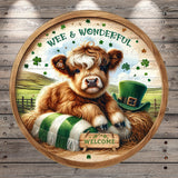 A round wooden sign with a cartoon cow wearing a green hat and surrounded by shamrocks, with the text "WEE & WONDERFUL" and a "WELCOME" sign below.