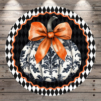 A decorative pumpkin with a large orange bow sits on a black and white checkered background.