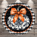 A decorative pumpkin with a large orange bow sits on a black and white checkered background.
