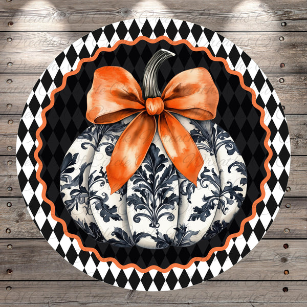 A decorative pumpkin with a large orange bow sits on a black and white checkered background.