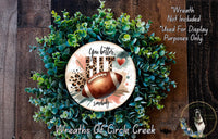 A wreath made of green leaves and a brown football, with the text "You better. Somebody somewhere" on it.