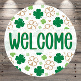 A circular welcome sign with the word "WELCOME" written in green letters, surrounded by a pattern of green shamrocks and hearts on a white background.