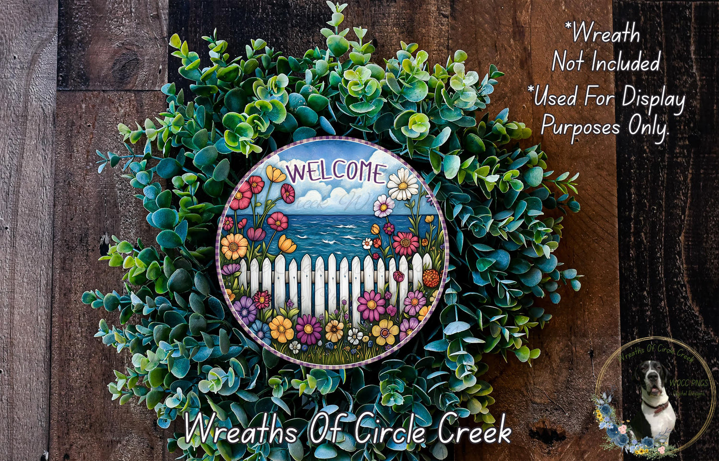 a wreath with a colorful design, including flowers and a wooden fence, hanging on a wooden wall. The wreath is surrounded by a lush green plant, creating a vibrant and welcoming atmosphere.