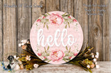 A decorative sign with the word "Hello" in white text, surrounded by a floral arrangement of pink and green flowers, placed on a wooden surface.
