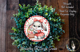 A wreath made of green leaves and flowers, featuring a cartoon rabbit wearing a red and white checkered dress and holding a basket of Easter eggs.
