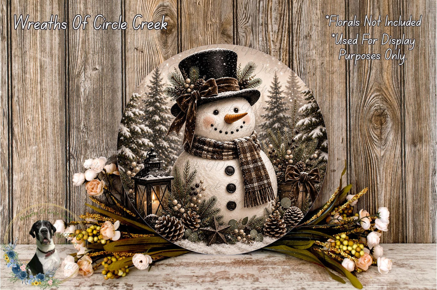 A snowman decoration with a lantern, pine cones, and flowers is displayed on a wooden surface, with a text overlay indicating that floral decorations are not included for display purposes.