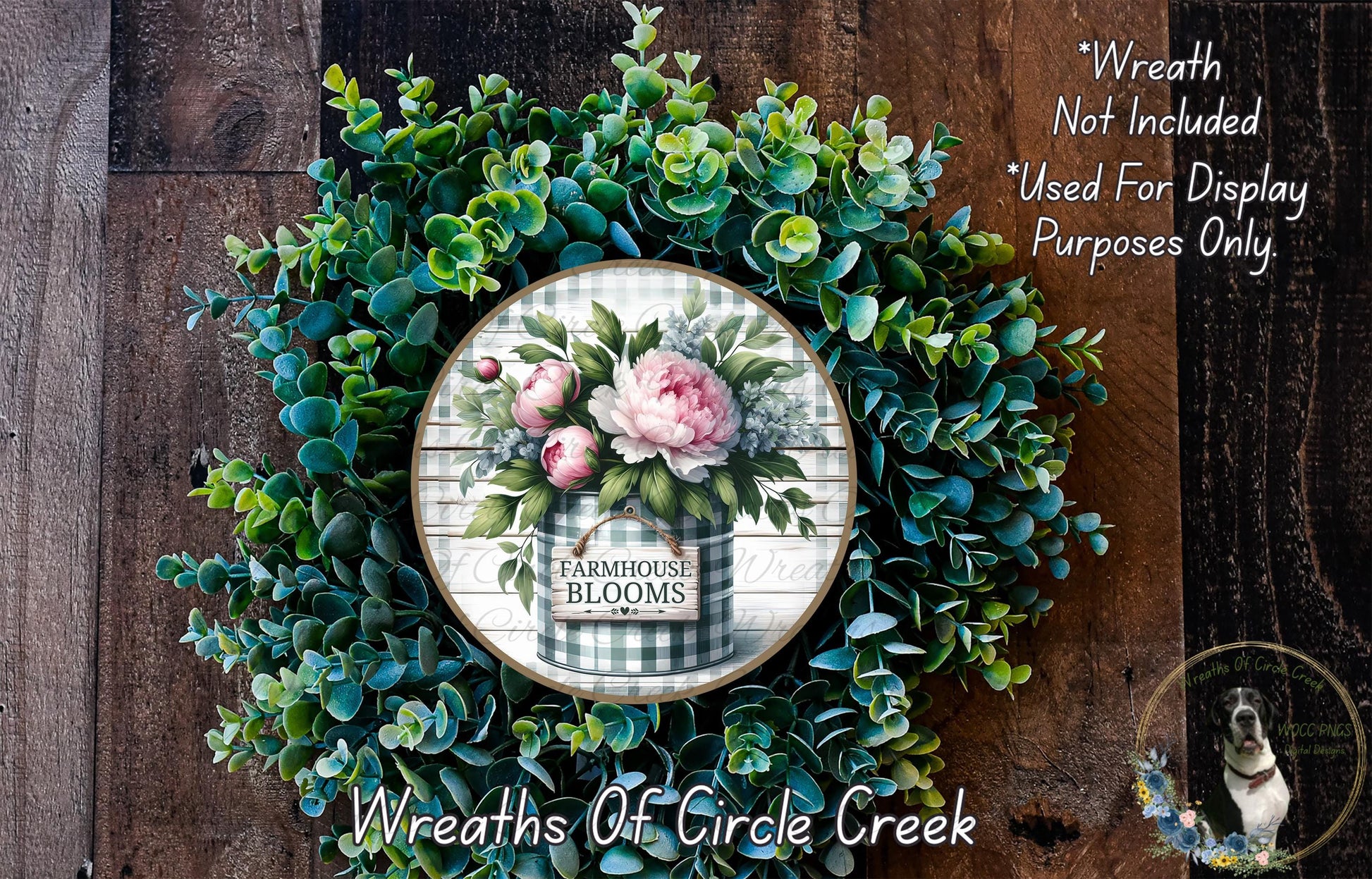 a wreath made of various green plants and flowers, including a large floral arrangement in the center. The wreath is displayed on a wooden surface, and there is a small sign or text that reads "Wreath Not Included * Used For Display Purposes Only".