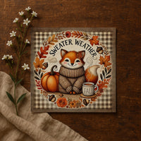 A cozy illustration of a fox wearing a sweater and surrounded by autumn-themed elements, including a pumpkin, flowers, and a cup of coffee, with the text "SWEATER WEATHER" and "FALL" prominently displayed.