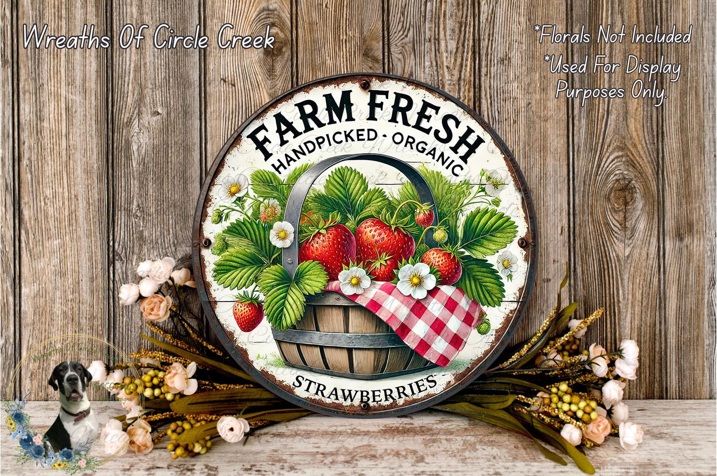 a rustic wooden wall with a round metal sign that reads "Farm Fresh Handpicked Organic Strawberries". The sign is surrounded by a basket of fresh strawberries and a wreath of flowers, creating a charming and inviting display.