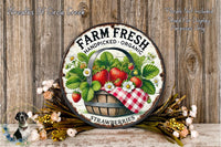 a rustic wooden wall with a round metal sign that reads "Farm Fresh Handpicked Organic Strawberries". The sign is surrounded by a basket of fresh strawberries and a wreath of flowers, creating a charming and inviting display.