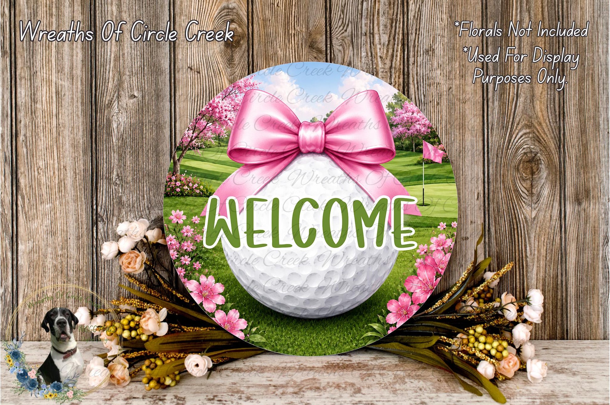 a golf ball surrounded by flowers and a pink bow, with the word "WELCOME" written on it. The background is a wooden fence, and there is a small bird in the bottom left corner.