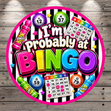 The image is a vibrant and colorful collage featuring various elements related to bingo, including numbers, bingo balls, and a large text that says "I'm probably at BINGO".