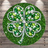 A round, glittery cloverleaf design made up of various green and white gemstones, including diamonds, set against a wooden background.