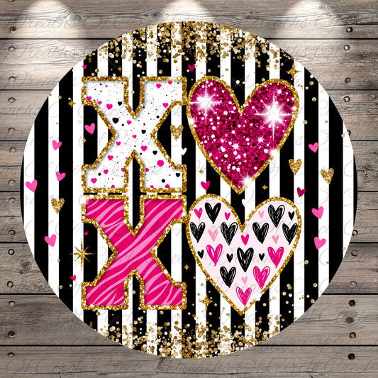 A circular design with a black and white striped background, featuring a large pink and white "X" surrounded by hearts and hearts in various colors.