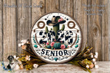 A decorative sign with the text "2026 SENIOR" surrounded by various floral elements, including a cactus, flowers, and a cowboy hat. The sign is placed on a wooden surface, with a floral arrangement in the foreground.