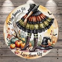 A whimsical illustration of a witch in a colorful, ruffled dress standing in a garden surrounded by pumpkins, bats, and a witch's hat. The text "If the boots fit, lace them up" is displayed around the witch, suggesting a playful or humorous message.