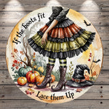 A whimsical illustration of a witch in a colorful, ruffled dress standing in a garden surrounded by pumpkins, bats, and a witch's hat. The text "If the boots fit, lace them up" is displayed around the witch, suggesting a playful or humorous message.