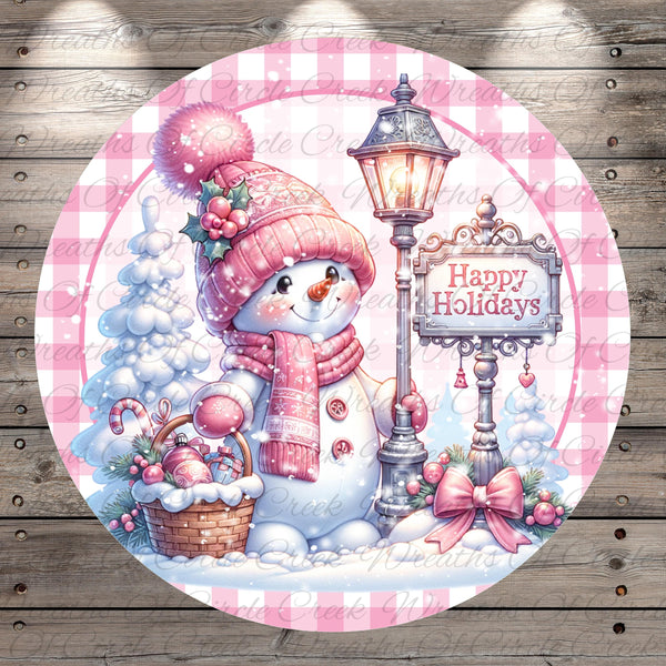 A cheerful snowman wearing a pink hat and scarf, holding a basket of candy canes, stands next to a lamp post with a "Happy Holidays" sign. The background features a snowy landscape with trees and a lamppost.
