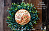 a wreath made of various autumn leaves and apples, with a sign that reads "Autumn Leaves & Apple Trees" in the center. The wreath is displayed on a wooden surface, and there is a small dog in the bottom right corner of the image.