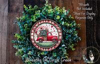 A wreath made of green foliage and a red truck with a "Special Delivery" sign on it, placed on a wooden surface.