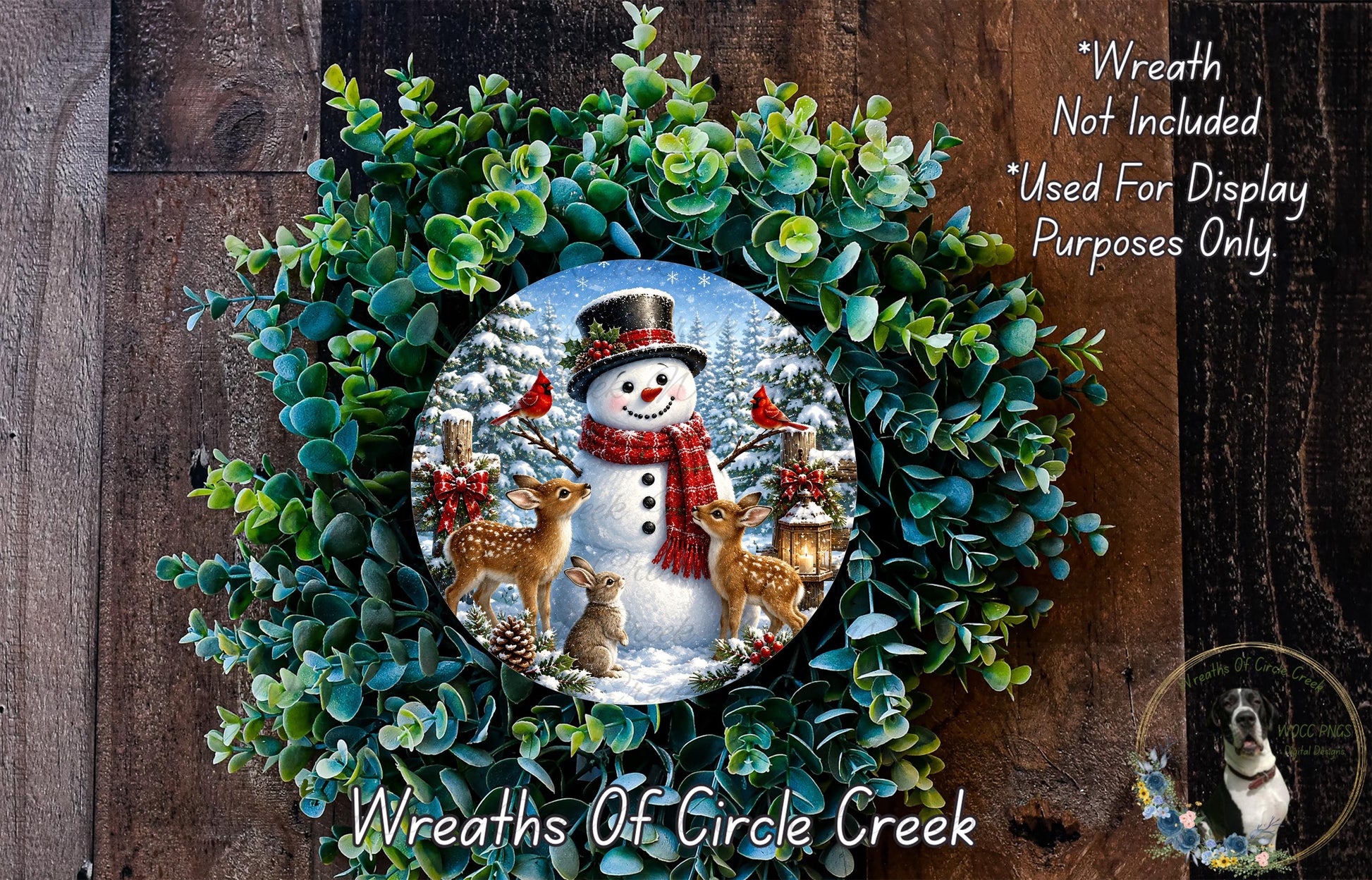 A wreath featuring a snowman, deer, and bird, surrounded by a lush green wreath. The wreath is displayed on a wooden surface, and there is a text overlay that reads "Wreath Not Included * Used For Display Purposes Only".