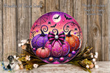 a decorative Halloween wreath with a spider web design, a full moon, and bats. The wreath is adorned with three pumpkins in various colors and sizes, and is surrounded by flowers and greenery. The background is a wooden wall with a spider web.