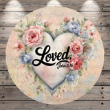 A heart-shaped design with pink and blue flowers surrounding it, and the text "Loved." written in cursive.
