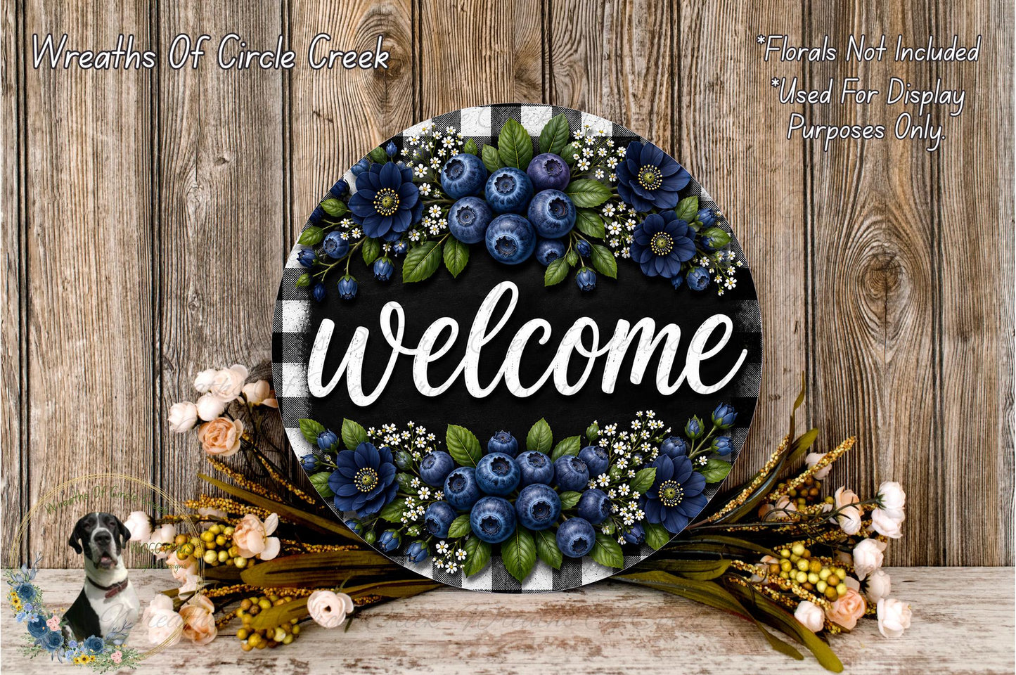 a decorative welcome sign with a floral design, surrounded by various flowers and foliage. The sign is placed on a wooden surface, and there is a text overlay that reads "Welcome" and "Flowers Not Included Used For Display Purposes Only".