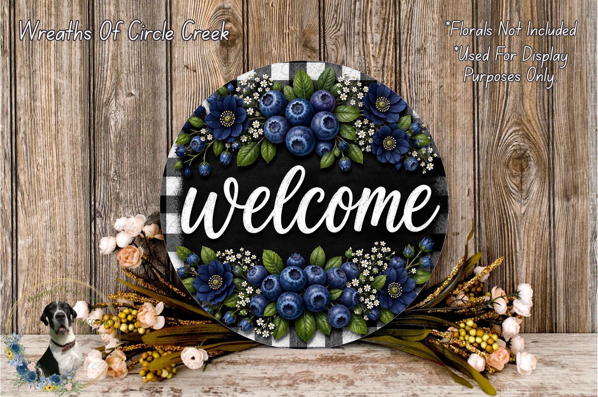 a decorative welcome sign with a floral design, surrounded by various flowers and foliage. The sign is placed on a wooden surface, and there is a text overlay that reads "Welcome" and "Flowers Not Included Used For Display Purposes Only".