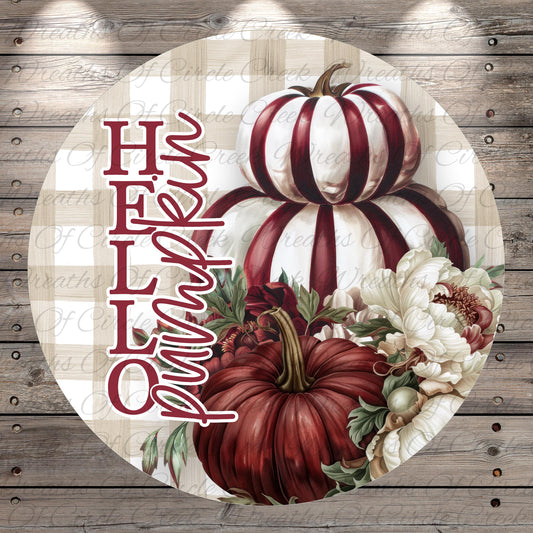 A circular sign with a floral design featuring two large pumpkins and white and red flowers, along with the text "Hello" written in cursive.