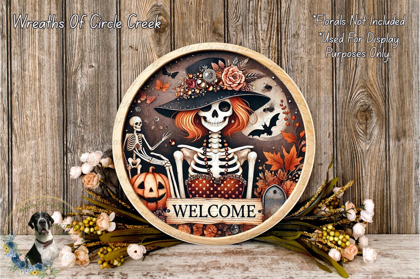 a decorative wreath with a skeleton wearing a hat and holding a pumpkin, surrounded by flowers and leaves. The wreath has the word "WELCOME" written on it.