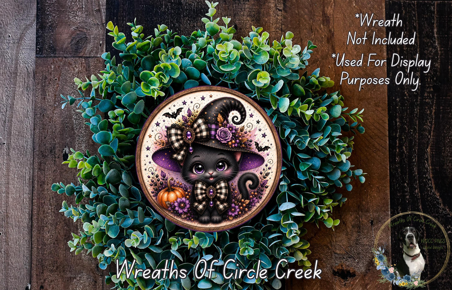 A wreath featuring a black cat wearing a witch's hat, surrounded by green foliage and a pumpkin.