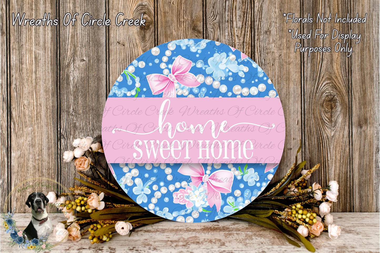 a round sign with the text "Home Sweet Home" displayed on it, surrounded by a floral arrangement and a wooden background.